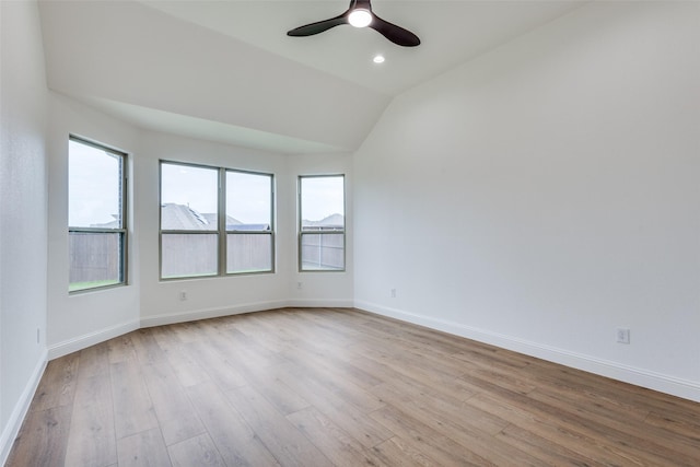 empty room featuring lofted ceiling, light wood finished floors, and baseboards