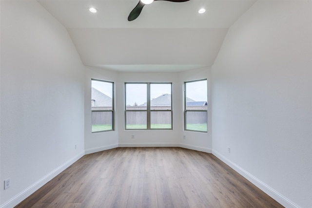 empty room with lofted ceiling, baseboards, wood finished floors, and recessed lighting