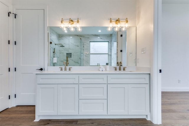 bathroom featuring wood finished floors, a sink, and a marble finish shower