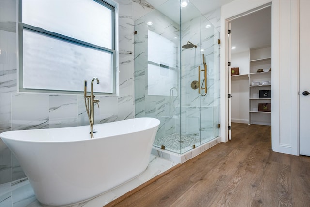 bathroom with a freestanding tub, plenty of natural light, a marble finish shower, and wood finished floors