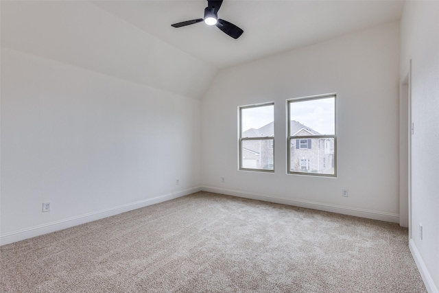 empty room featuring lofted ceiling, ceiling fan, carpet, and baseboards