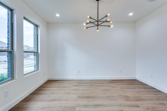 unfurnished room with light wood finished floors, an inviting chandelier, recessed lighting, and baseboards