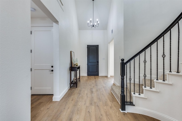 entryway with a notable chandelier, light wood-style flooring, baseboards, and stairs