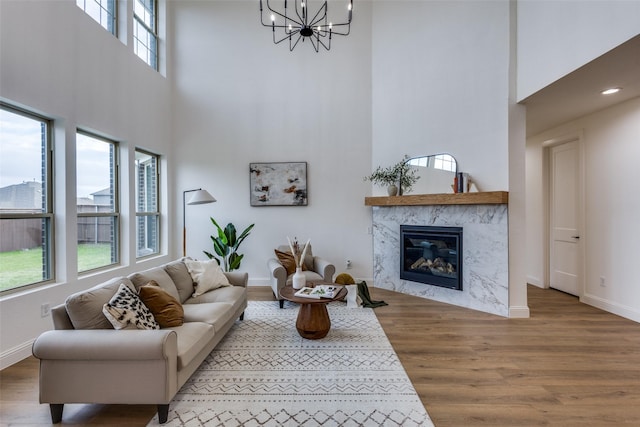 living room featuring a notable chandelier, a fireplace, baseboards, and wood finished floors