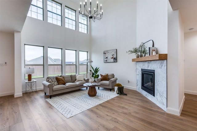 living room featuring a notable chandelier, a fireplace, light wood-style flooring, and baseboards