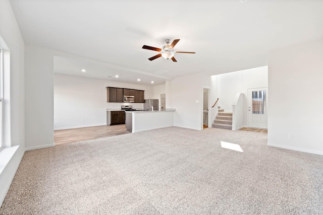 unfurnished living room with ceiling fan and light colored carpet