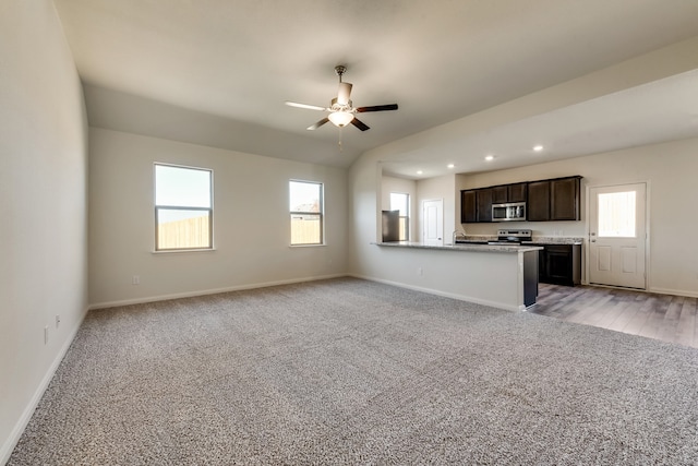 unfurnished living room featuring a healthy amount of sunlight, ceiling fan, and light colored carpet