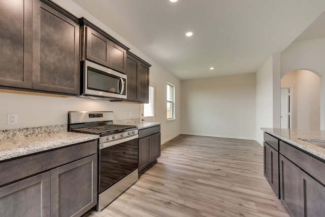 kitchen featuring sink, light hardwood / wood-style floors, light stone counters, dark brown cabinetry, and stainless steel appliances