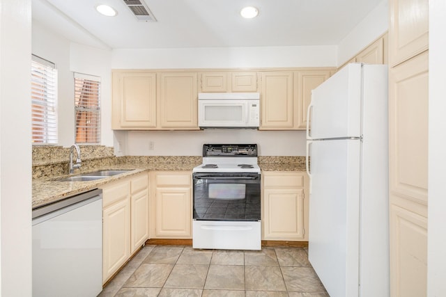 kitchen featuring cream cabinets, light stone counters, sink, and white appliances