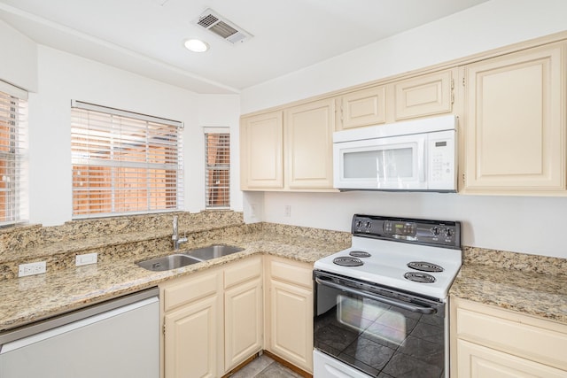 kitchen featuring light stone counters, white appliances, sink, and cream cabinets