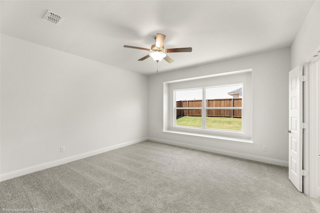 carpeted spare room featuring baseboards, visible vents, and ceiling fan