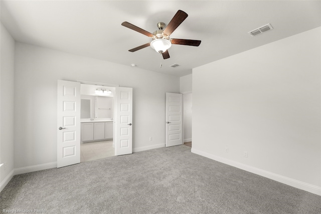 unfurnished bedroom featuring ensuite bath, ceiling fan, and light colored carpet