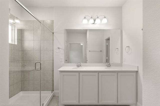 bathroom with a sink, a shower stall, and double vanity