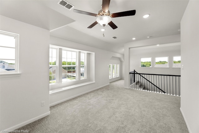 spare room featuring a wealth of natural light, light carpet, and ceiling fan