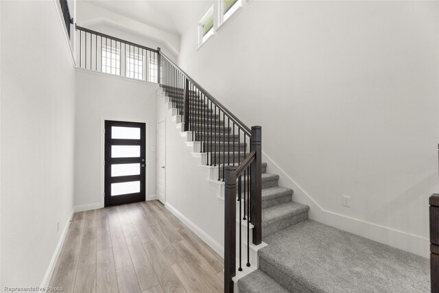 entrance foyer with a towering ceiling and light wood-type flooring