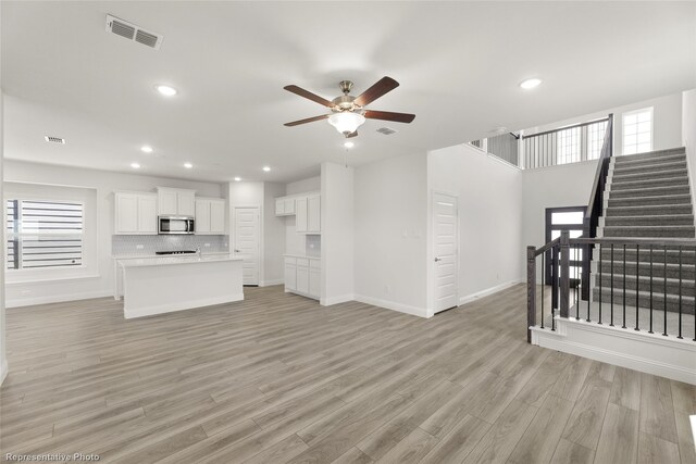 living room with ceiling fan, plenty of natural light, and light hardwood / wood-style floors