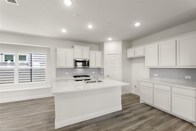 kitchen with stainless steel microwave, light countertops, tasteful backsplash, and white cabinets