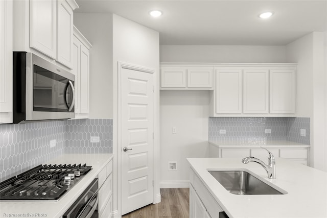 kitchen featuring light countertops, appliances with stainless steel finishes, white cabinetry, and a sink