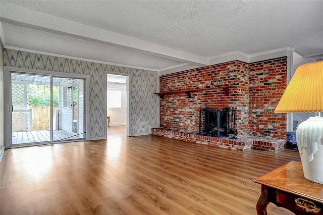 living room featuring beam ceiling, a brick fireplace, hardwood / wood-style floors, a textured ceiling, and ornamental molding