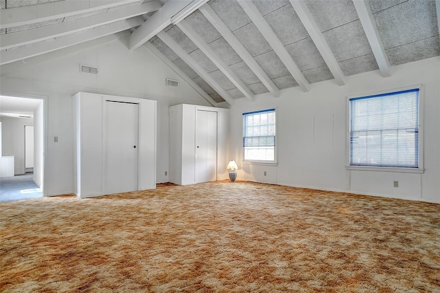 unfurnished bedroom with beam ceiling, carpet, two closets, and high vaulted ceiling