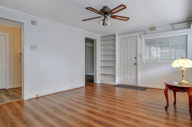 entrance foyer featuring ceiling fan, a textured ceiling, and ornamental molding