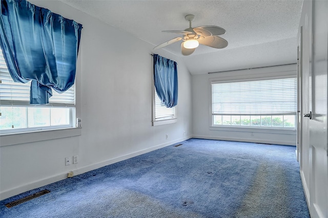 carpeted spare room featuring a textured ceiling, ceiling fan, and vaulted ceiling