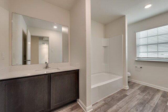 full bathroom featuring hardwood / wood-style floors, vanity, toilet, and shower / tub combination