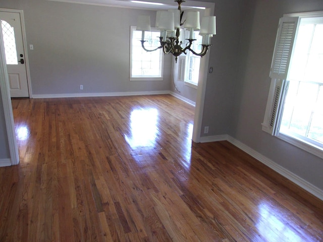 unfurnished dining area featuring dark hardwood / wood-style flooring and an inviting chandelier