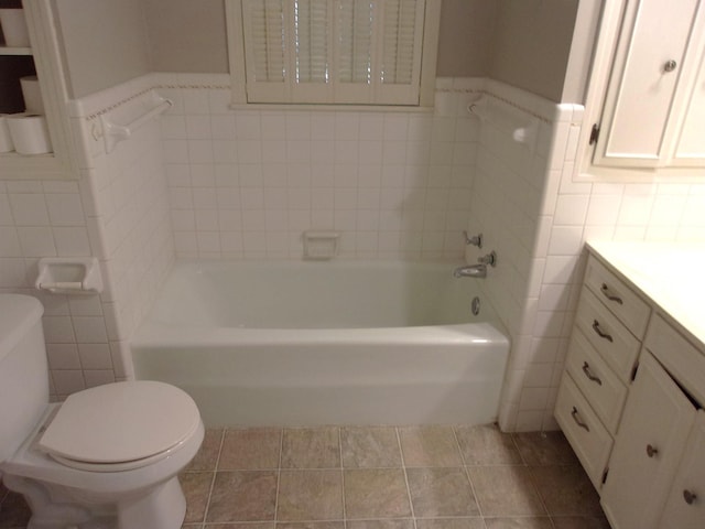 bathroom featuring vanity, a tub to relax in, tile walls, and toilet