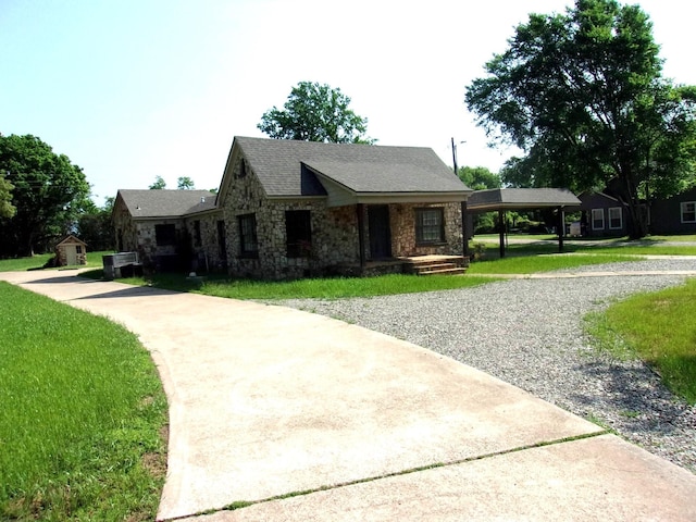 view of front of property featuring a carport, a storage unit, and a front yard