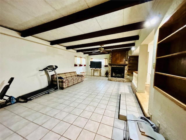 interior space featuring light tile patterned floors, beamed ceiling, a large fireplace, and a ceiling fan