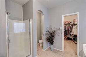 bathroom featuring toilet, a shower with door, and tile patterned flooring