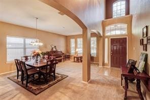 carpeted foyer entrance featuring a chandelier and plenty of natural light