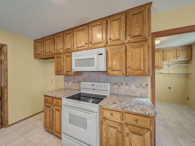 kitchen featuring tasteful backsplash, white appliances, and light stone countertops