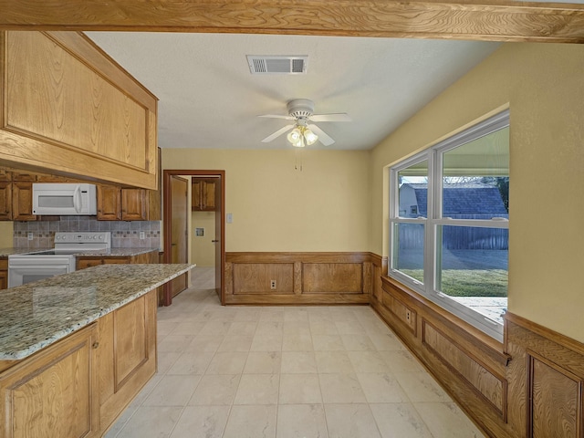 kitchen with light stone countertops, plenty of natural light, white appliances, and decorative backsplash