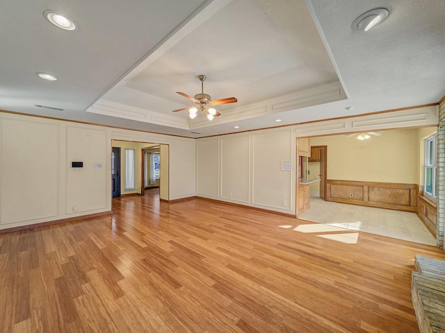 unfurnished room with a tray ceiling, light hardwood / wood-style flooring, and ceiling fan