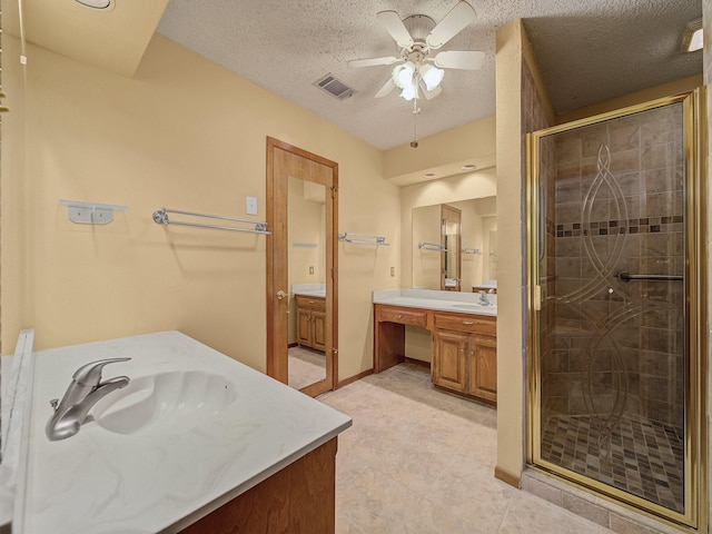 bathroom featuring vanity, ceiling fan, an enclosed shower, and a textured ceiling