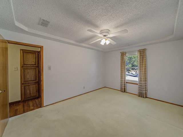 spare room featuring carpet, a textured ceiling, ceiling fan, and a tray ceiling