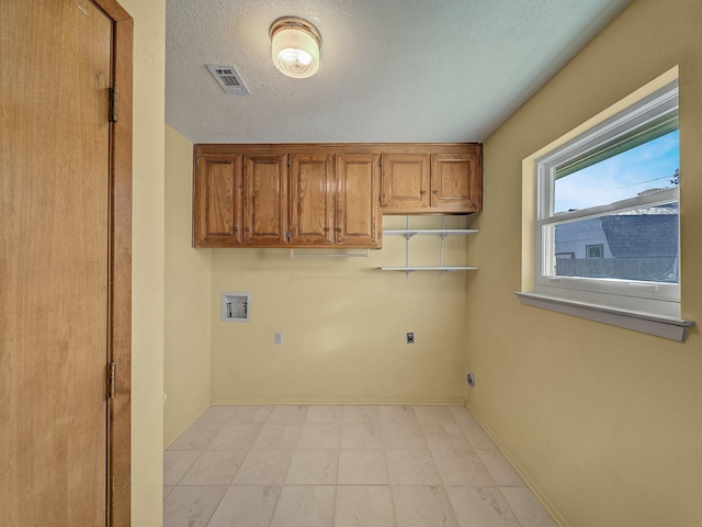 washroom featuring electric dryer hookup, washer hookup, cabinets, and a textured ceiling