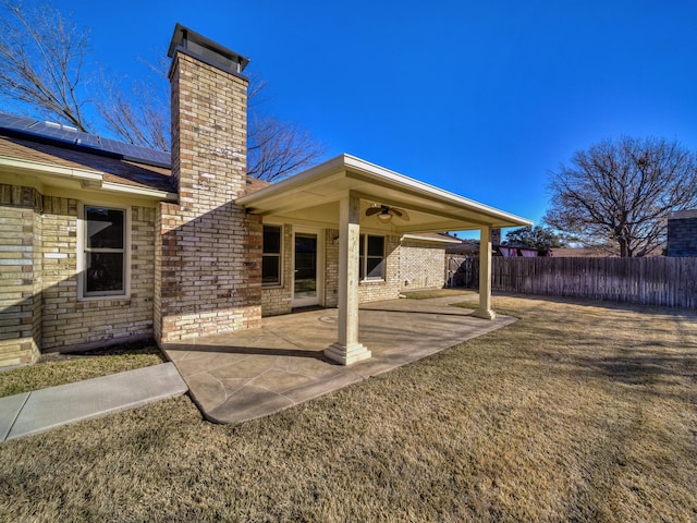 rear view of property featuring a patio, a yard, ceiling fan, and solar panels