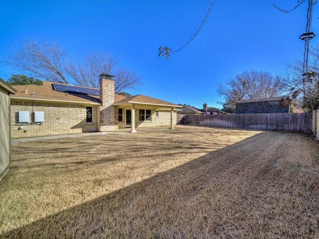 rear view of property featuring a patio area and solar panels