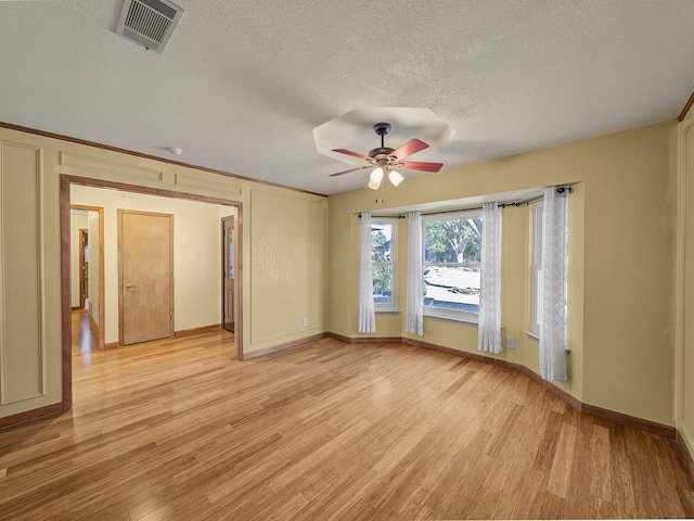 unfurnished room with ceiling fan, a textured ceiling, and light wood-type flooring