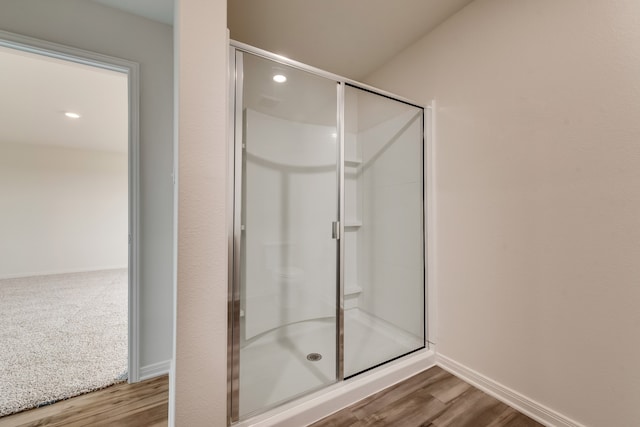 bathroom with wood-type flooring and an enclosed shower