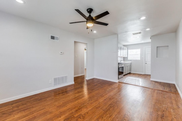 unfurnished living room with hardwood / wood-style flooring, ceiling fan, and sink