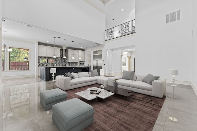 living room featuring sink, a high ceiling, and a chandelier