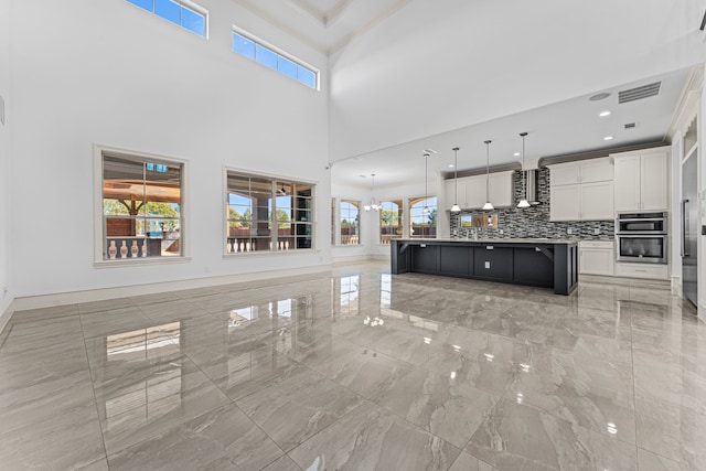 unfurnished living room with a high ceiling and a wealth of natural light