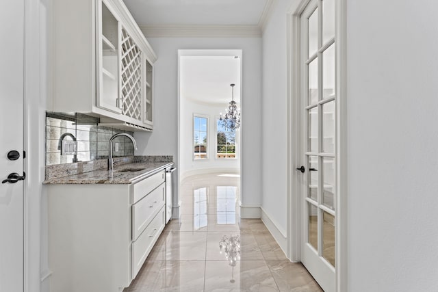 bar featuring white cabinets, tasteful backsplash, crown molding, and sink