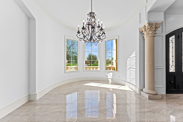 foyer featuring decorative columns, ornamental molding, and a notable chandelier