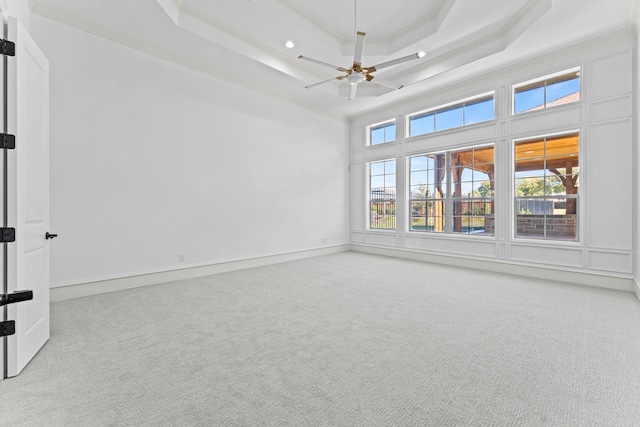 carpeted spare room with ceiling fan, ornamental molding, a high ceiling, and a tray ceiling