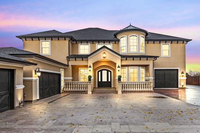 view of front of home featuring covered porch, french doors, and a garage